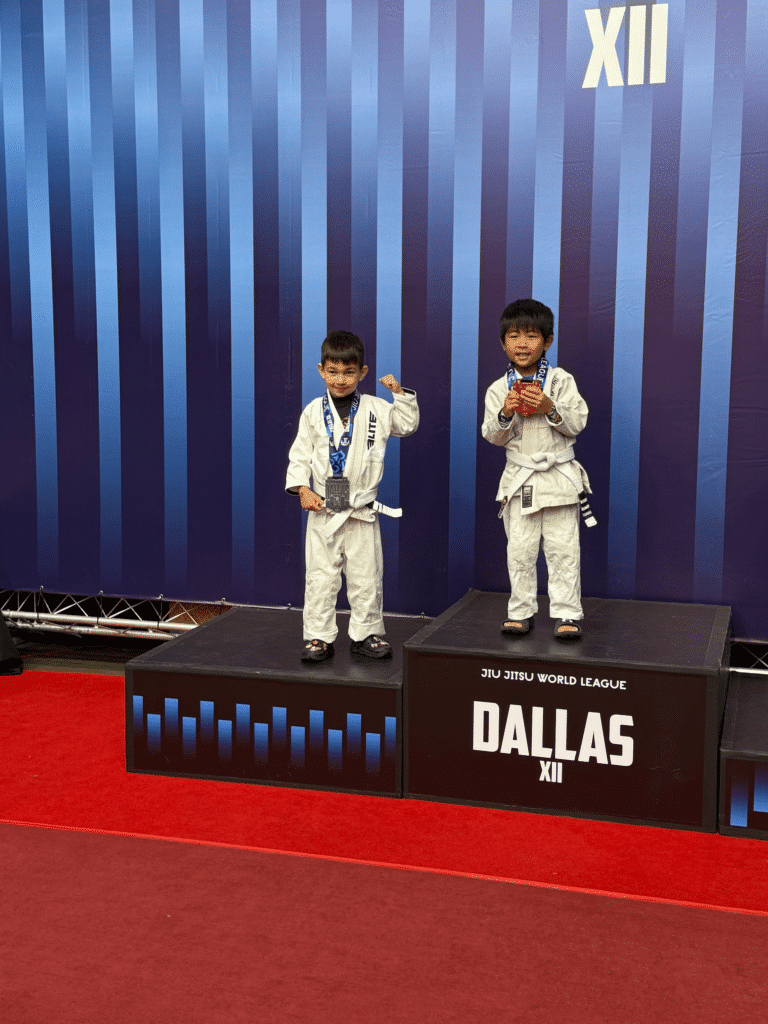 Wolfpack MMA kid student in gi on winners podium at an event.